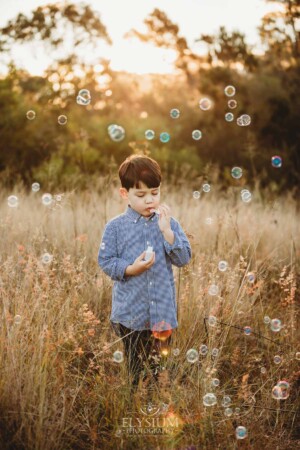 Family Photography: a boy blowing bubbles in a grassy field