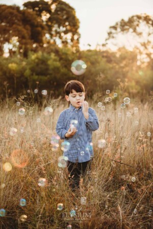 Family Photography: a boy blowing bubbles in a grassy field