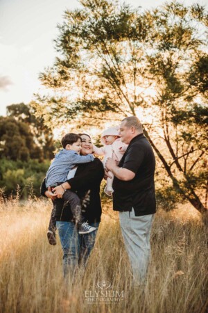 Family Photography: parents cuddle their babies in a grassy field at sunset
