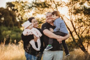 Family Photography: parents cuddle their kids in a grassy field