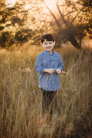 Family Photography: a boy stands in a grassy field at sunset