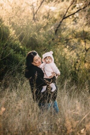 Family Photography: a mother cuddles her baby girl in a grassy field