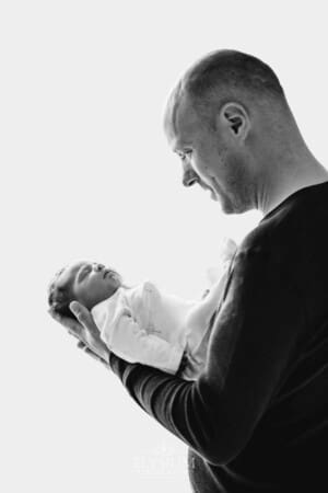 A father gently holds his newborn baby girl