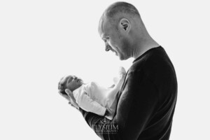 A father gently holds his newborn baby girl