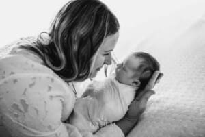 A mother holds her baby girl on a bed