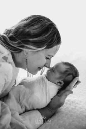 A mother presses her nose to her baby girl's nose