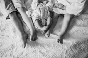 Three siblings sit with their feet together