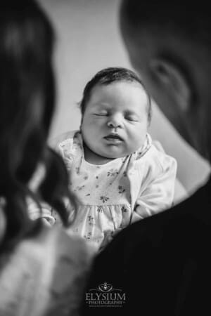 Parents sit holding their baby girl between them