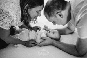 Parents hold their baby girl between them on a bed