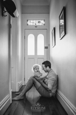 Newborn Photography: a dad sits with his little boy in a hallway