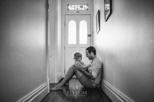 Newborn Photography: a little boy sitting in his dad's lap in their hallway