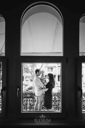 Newborn Photography: looking through a window as parents hold their baby boy