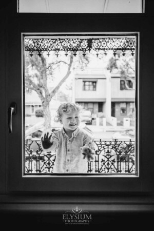 Newborn Photography: a little boy smiles through a window