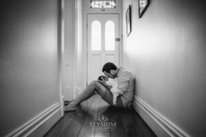 Newborn Photography: a father sits in a hallway with his baby boy