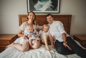 Newborn Photographer: a family sitting on a bed with their baby boy