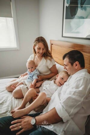 Newborn Photographer: a family sitting on a bed with their baby boy