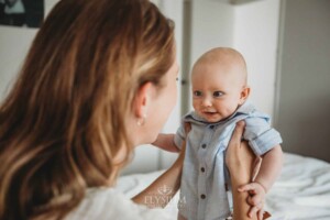 Newborn Photographer: a mother holds her baby boy as he smiles at her