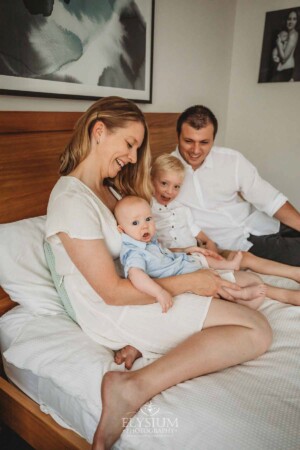 Newborn Photographer: a family sitting on a bed with their baby boy