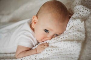 Newborn Photographer: a baby boy with blue eyes lays on a white blanket