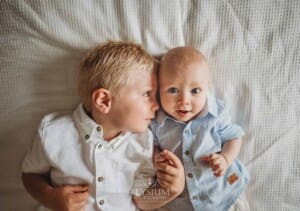 Newborn Photographer: a little boy snuggles his baby brother on a bed