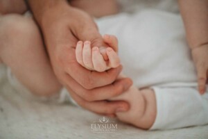 Newborn Photographer: a father holds his baby boy's tiny hand