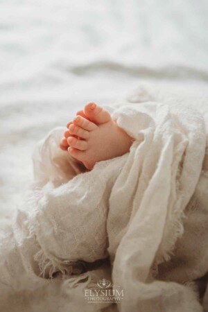 Newborn Photographer: a baby boy's little feet poke out from a white wrap