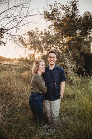 Engagement Photographer: a couple standing in long grass hugging