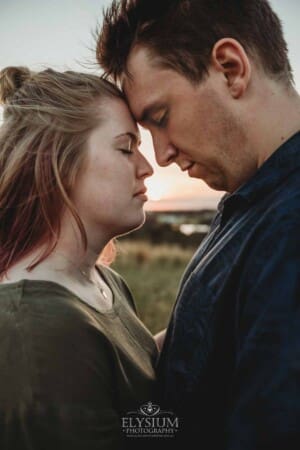 Engagement Photographer: a couple standing with foreheads together at sunset