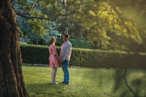 Engagement Photography: a couple stand holding hands in a garden at sunset