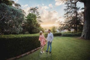 Engagement Photography: a couple stand in a garden holding hands at sunset