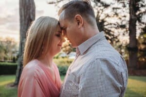Engagement Photography: a couple stand with foreheads pressed together at sunset
