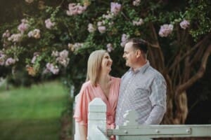 Engagement Photography: a couple stand together in front of pink blossom trees