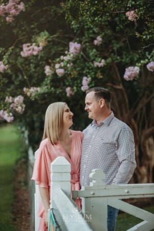 Engagement Photography: a couple stand together in front of pink blossom trees