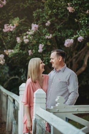 Engagement Photography: a couple stand together in front of pink blossom trees