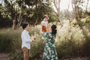 A family play with their baby boy lifting him into the air