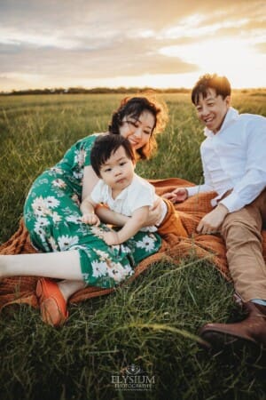 A family sit on a blanket with their baby at sunset