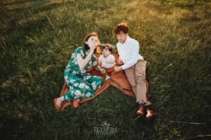 Parents sit on a blanket with their baby and blow bubbles