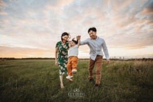 A family hold their baby's hands and swing him as they walk