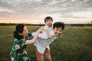 A father carries his baby boy on his back at sunset