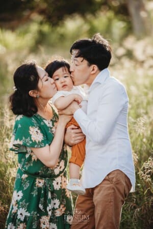 A family cuddle their baby boy and give him kisses on the cheeks