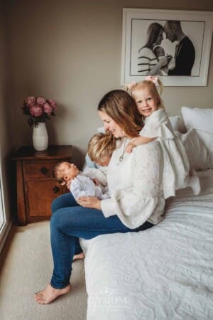 A mother shows her children their newborn sister