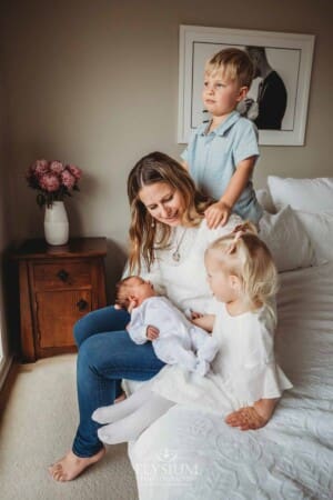 A mother shows her children their newborn sister