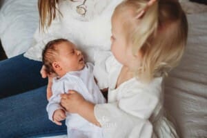 A little girl holds her baby sister in her arms