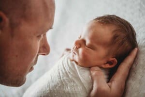 A baby girl lays sleeping in her dad's hands