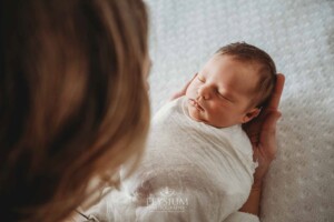 A newborn baby girl lays sleeping in her mum's hands