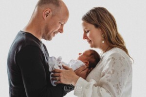 Parents hold their new baby girl in their arms between them