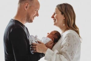 Parents hold their baby girl in their arms between them