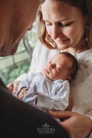 Parents hold their newborn baby girl in their arms between them