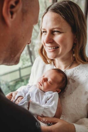 Parents hold their baby girl in their arms between them