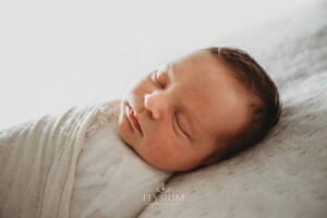 A baby girl lays on a white bed sleeping